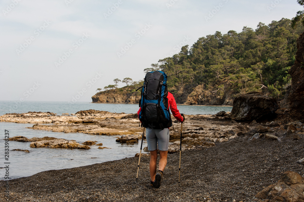 Fototapeta premium Girl walking on the beach with hiking backpack