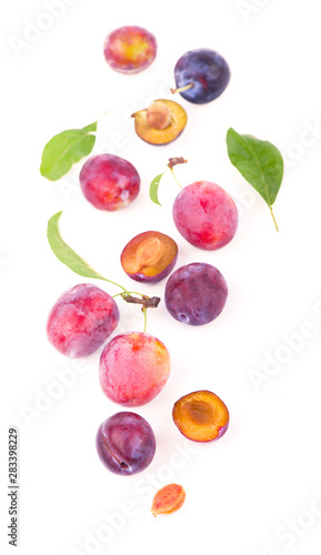 Ripe plums with leaves close up on white background