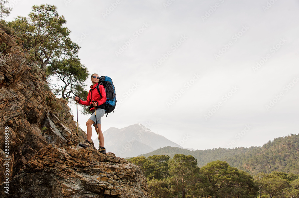 Sporty woman standing on the rock with hiking backpack