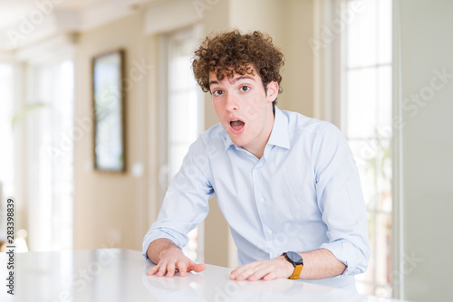 Young business man with curly read head afraid and shocked with surprise and amazed expression, fear and excited face.