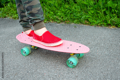 Cropped view of a teenager in red sneakers with a skateboard, outdoors.
