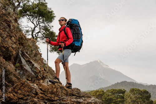 Sporty girl standing on the rock with hiking backpack