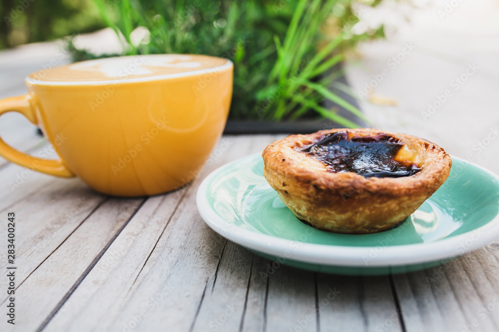 First-person view of a dessert and a cup of coffee - sweet cake and cappuccino on a wooden table First-person view of a dessert and a cup of coffee - sweet cake and cappuccino on a wooden table