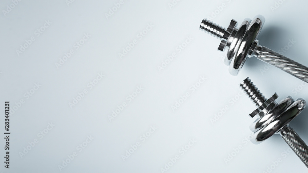 Metal, chrome dumbbell on blue background, workout, fitness theme Metal, chrome dumbbell on blue background, workout, fitness theme