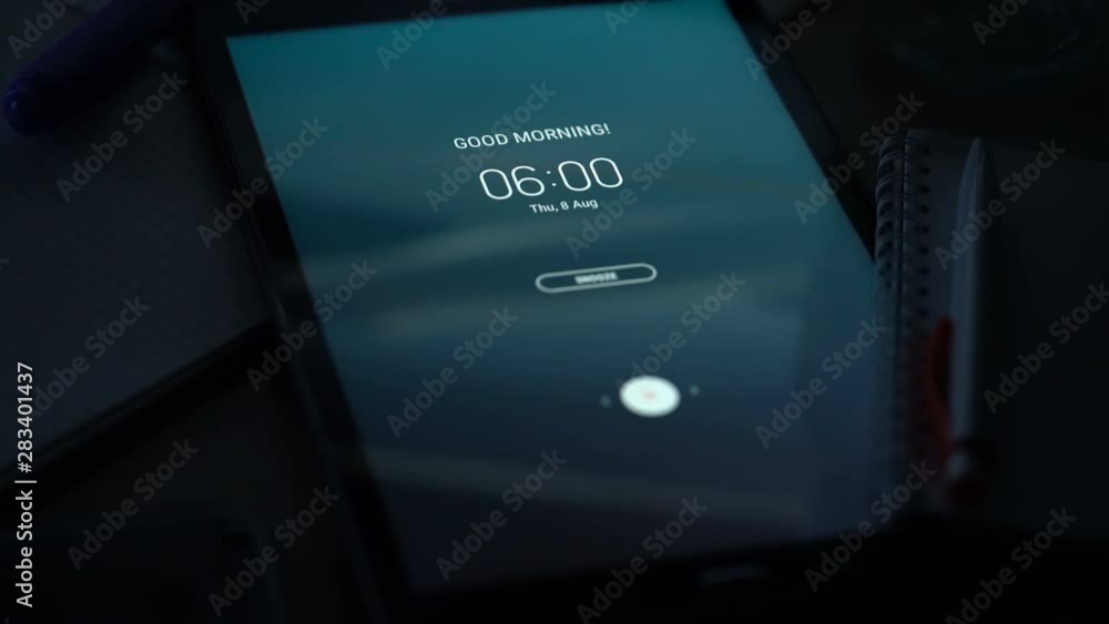 Good morning alarm clock on the tab on the desktop in the dark room , close-up Good morning alarm clock on the tab on the desktop in the dark room , close-up