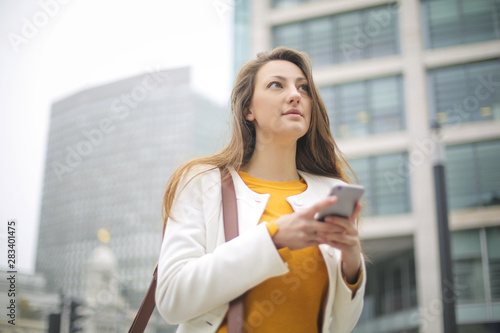 Photography Student walking in the street, chicking her phone