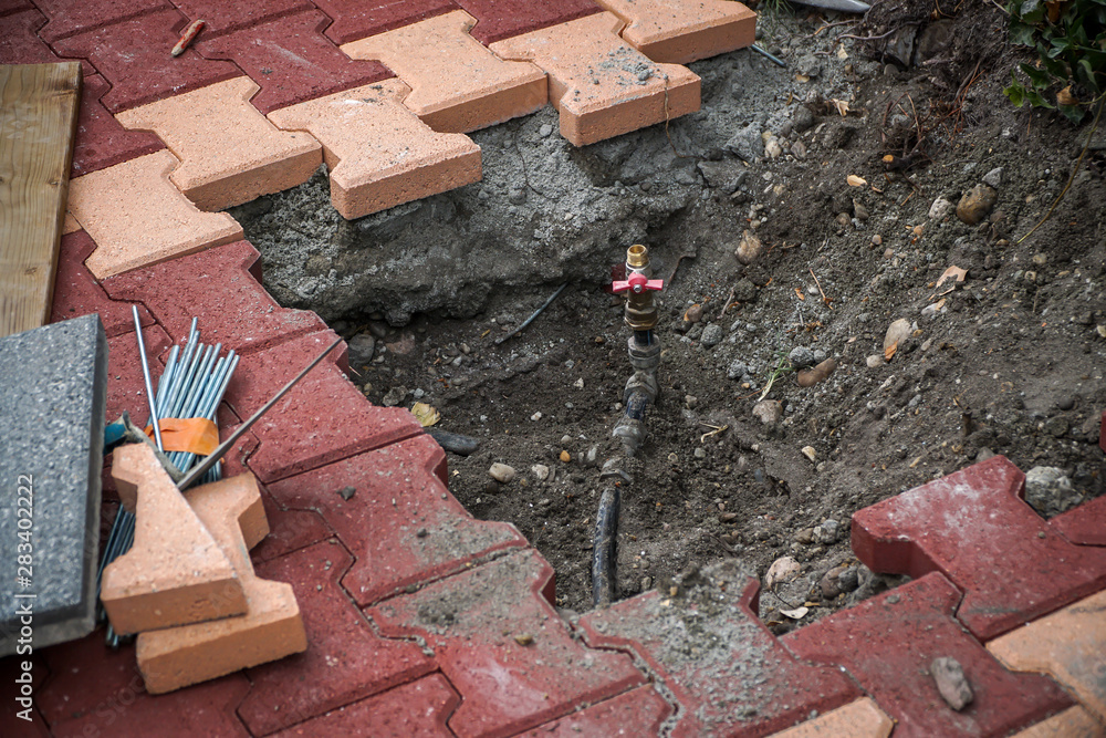 Laying of interlocking pavers and water pipes StockFoto Adobe Stock