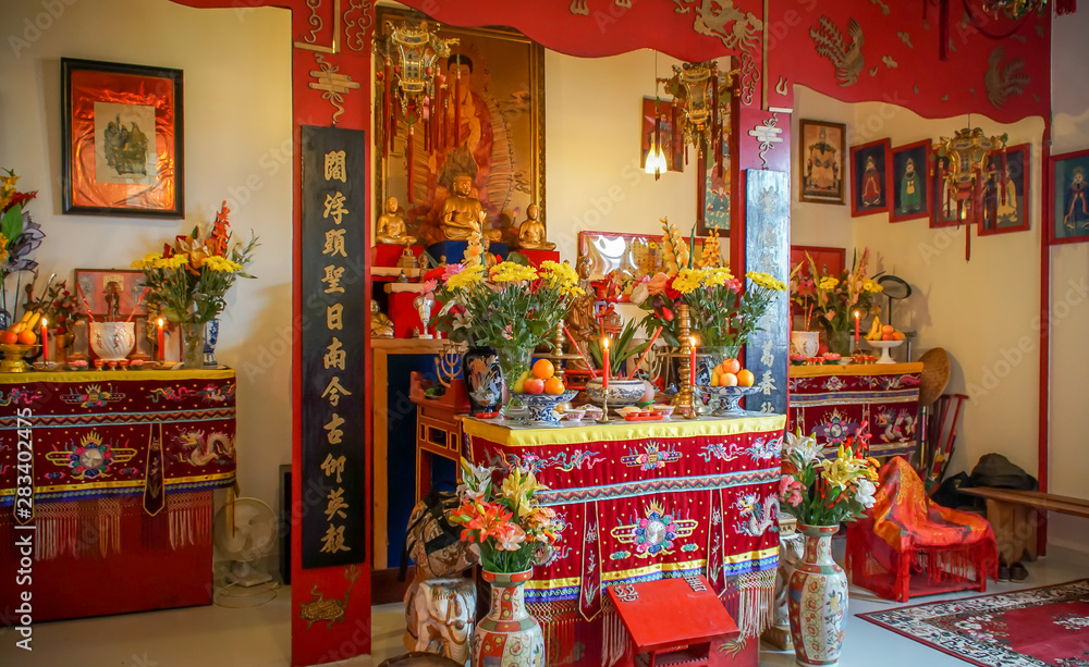 Interior of a vietnamese temple in france, open to public, with statues, offerings and objects of worship.