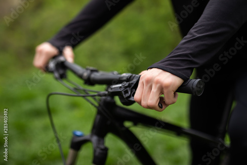 A man is riding a bicycle in a forest in the open air close-up. Park, active recreation, sports and a healthy lifestyle. Hands of a man on the wheel of a bicycle. Steering wheel bike close-up.