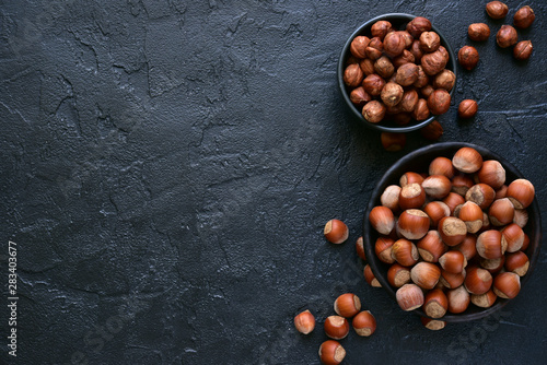 Peeled and unpeeled hazelnuts in a bowl.Top view with copy space. photo