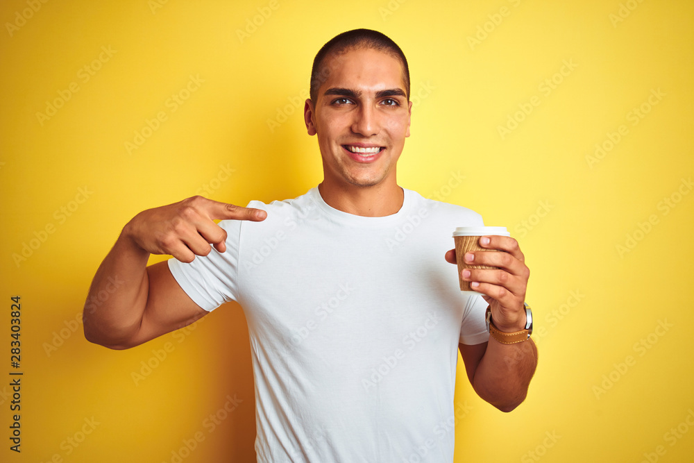 Young handsome man drinking a take away glass of coffee over yellow isolated background very happy pointing with hand and finger Young handsome man drinking a take away glass of coffee over yellow isolated background very happy pointing with hand and finger