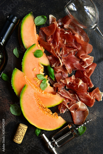 Sliced melon and jamon or prosciutto with bottle of red wine.Top view with copy space. photo