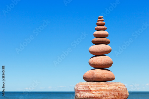 High Rock zen pyramid of pink stones on a background of blue sky and sea.