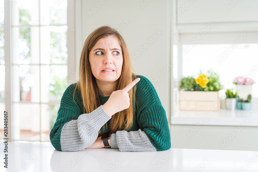 Young beautiful plus size woman wearing casual striped sweater Pointing aside worried and nervous with forefinger, concerned and surprised expression Young beautiful plus size woman wearing casual striped sweater Pointing aside worried and nervous with forefinger, concerned and surprised expression