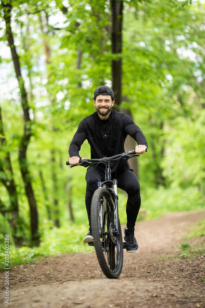 Young man riding mountain bike in forest
