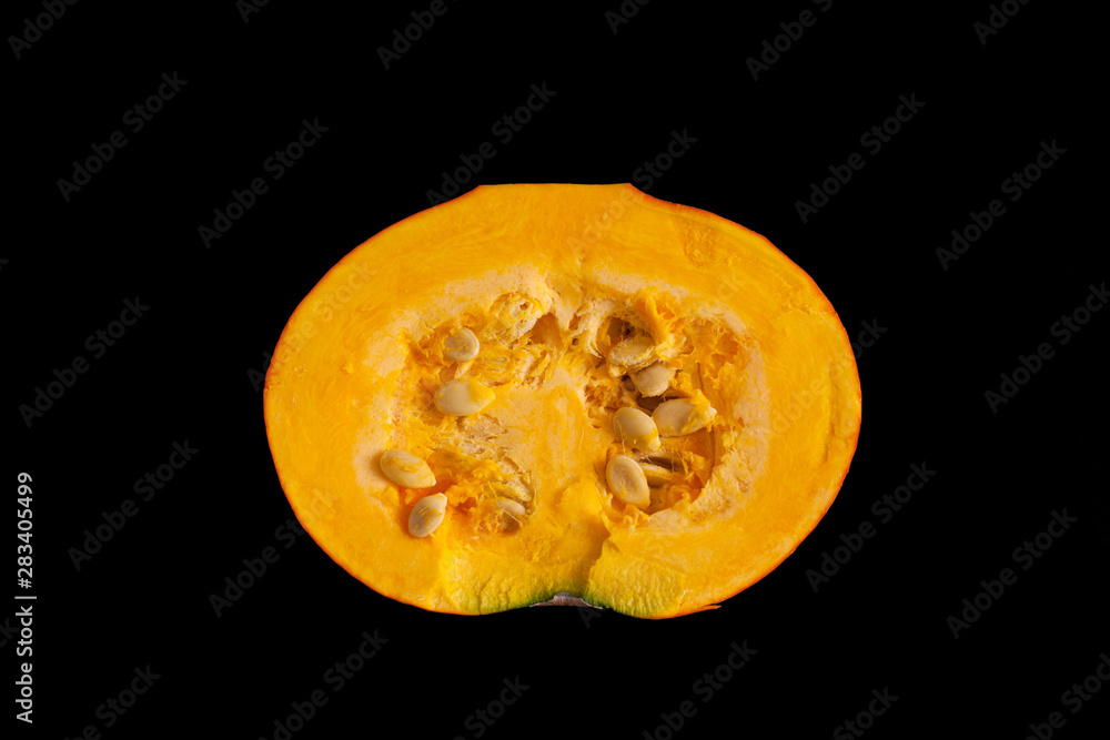 Half pumpkin with seeds isolated on black background