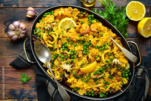 Classic valencian paella from rice with seafood and vegetables - traditional dish of spanish cuisine in a frying pan. Top view with copy space.