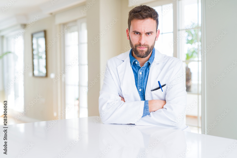 Handsome doctor man wearing medical coat at the clinic skeptic and nervous, disapproving expression on face with crossed arms. Negative person. Handsome doctor man wearing medical coat at the clinic skeptic and nervous, disapproving expression on face with crossed arms. Negative person.