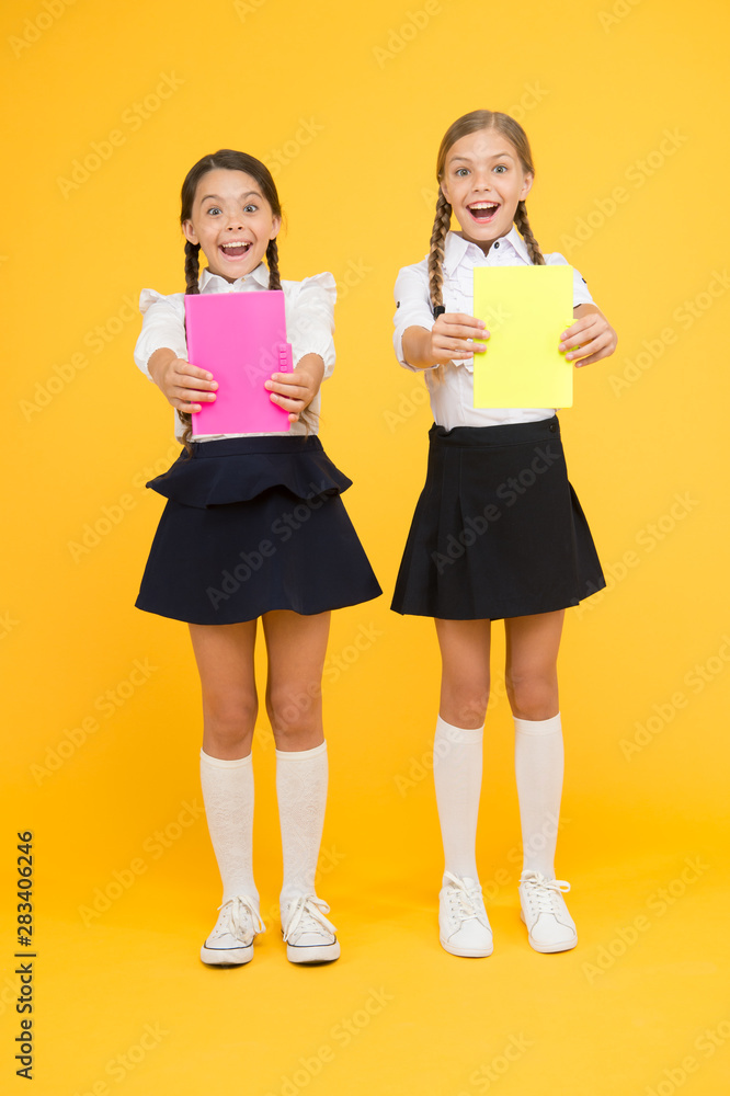 Children with school diaries for notes. Cute schoolgirls holding lesson books. School children learn reading books. Back to school. Little girls with workbooks for writing. Studying in small groups