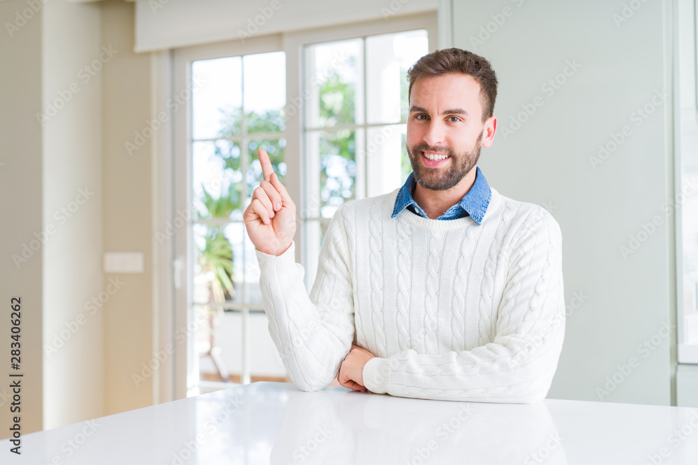 Fototapeta premium Handsome man wearing casual sweater with a big smile on face, pointing with hand and finger to the side looking at the camera.