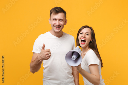 Konstfotografi Cheerful young couple friends guy girl in white blank empty t-shirts posing isolated on yellow orange background