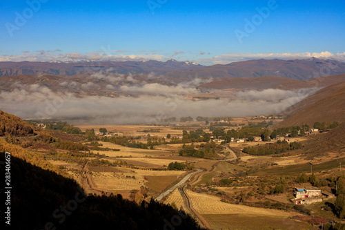 Countryside  Mist and Fog - Tibetan Farm situated in the grasslands of Western Sichuan Province  China. Colorful Tibetan building  agriculture farmland. High Altitude Plateau near Tibet  Ganzi