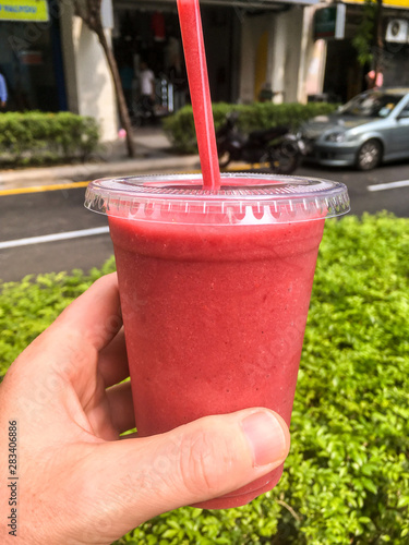 Hand held strawberry smoothie.