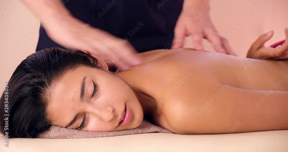 A young woman gets a massage procedure. Masseur makes back massage. A young woman gets a massage procedure. Masseur makes back massage.