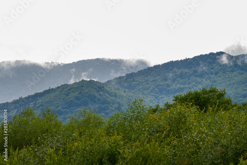 Moisture in the form of a pair of mountains rising into the clouds, mountain landscape, the water cycle in the nature, mountain evaporation