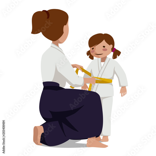 Woman in hakama and girl in keikogi tie a belt.