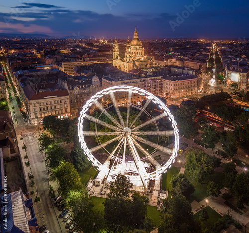 Budapest, Hungary - Aerial drone view of Elisabeth square at blue hour with illuminated ferris wheel and St. Stephen's Basilica at background. Summer evening in Budapest