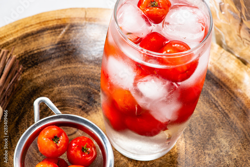 Acerola juice and Acerola fruit in a sieve and wooden background