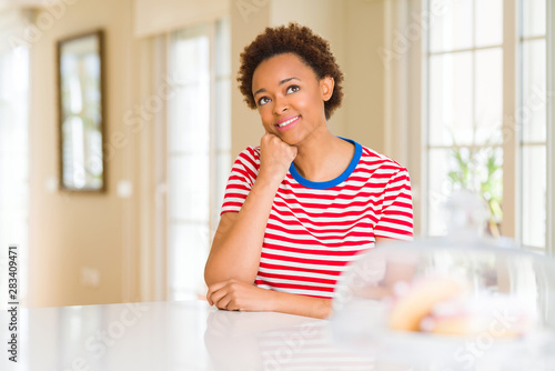 Young beautiful african american woman at home with hand on chin thinking about question  pensive expression. Smiling with thoughtful face. Doubt concept.