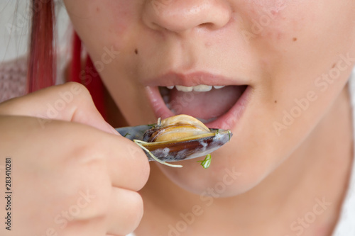 Girl eating oysters, snails in a restaurant, eating seafood, close-up © Anelo
