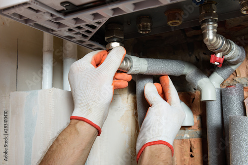 The worker is installing the gas boiler pipes.