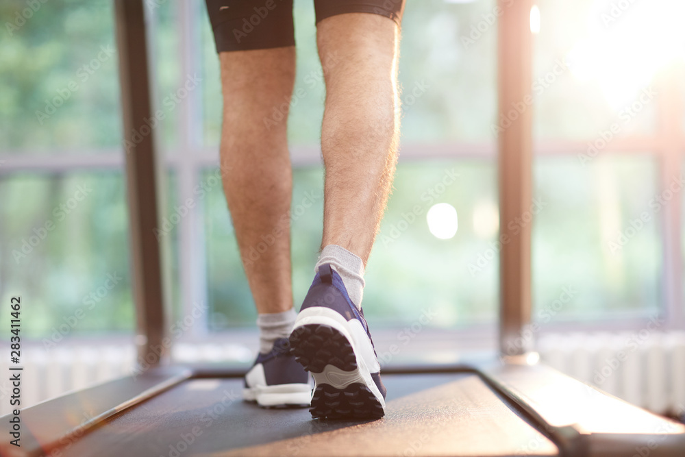 Back view of muscular male legs running on treadmill in gym, copy space Back view of muscular male legs running on treadmill in gym, copy space
