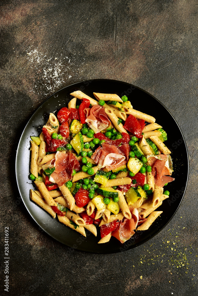 Penne pasta with grilled vegetables and prosciutto. Top view with copy space. Penne pasta with grilled vegetables and prosciutto. Top view with copy space.