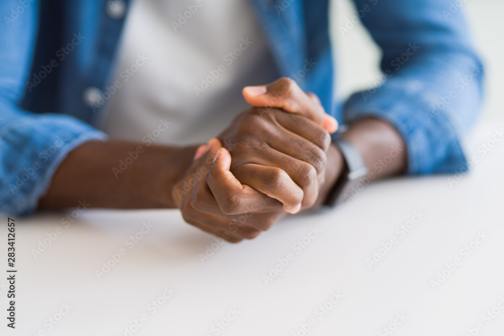 Close up of crossed hands of african man over table Close up of crossed hands of african man over table