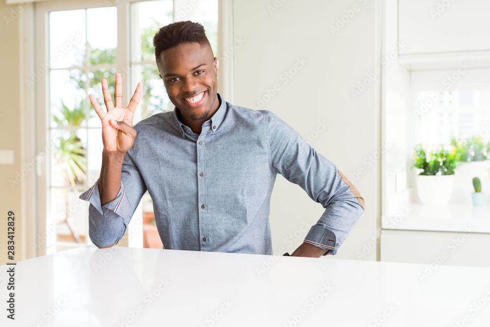 Handsome african american man on white table showing and pointing up with fingers number four while smiling confident and happy.