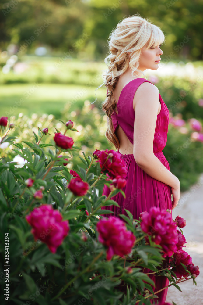 Outdoor close up portrait of beautiful young woman with long blonde hair, makeup, posing in the blooming garden. Female spring fashion concept Outdoor close up portrait of beautiful young woman with long blonde hair, makeup, posing in the blooming garden. Female spring fashion concept