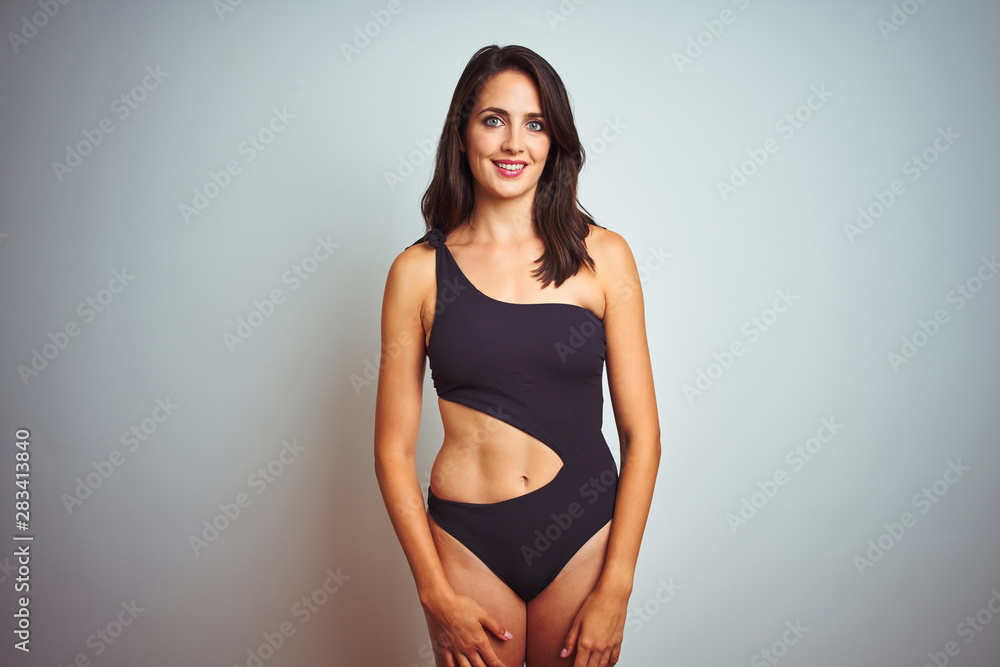 Beautiful woman wearing bikini swimwear over white isolated background with a happy and cool smile on face. Lucky person. Beautiful woman wearing bikini swimwear over white isolated background with a happy and cool smile on face. Lucky person.