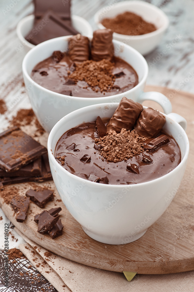 Two mugs of a hot chocolate with chocolate sticks on a wooden board Two mugs of a hot chocolate with chocolate sticks on a wooden board