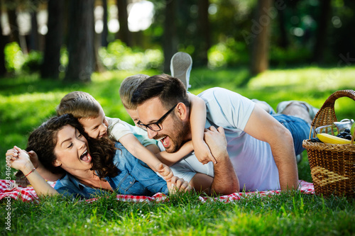 Happy male and female playing and enjoying picnic with children outside