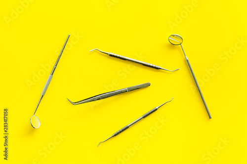 Dentist work desk with tools for teeth on yellow background top view © 9dreamstudio