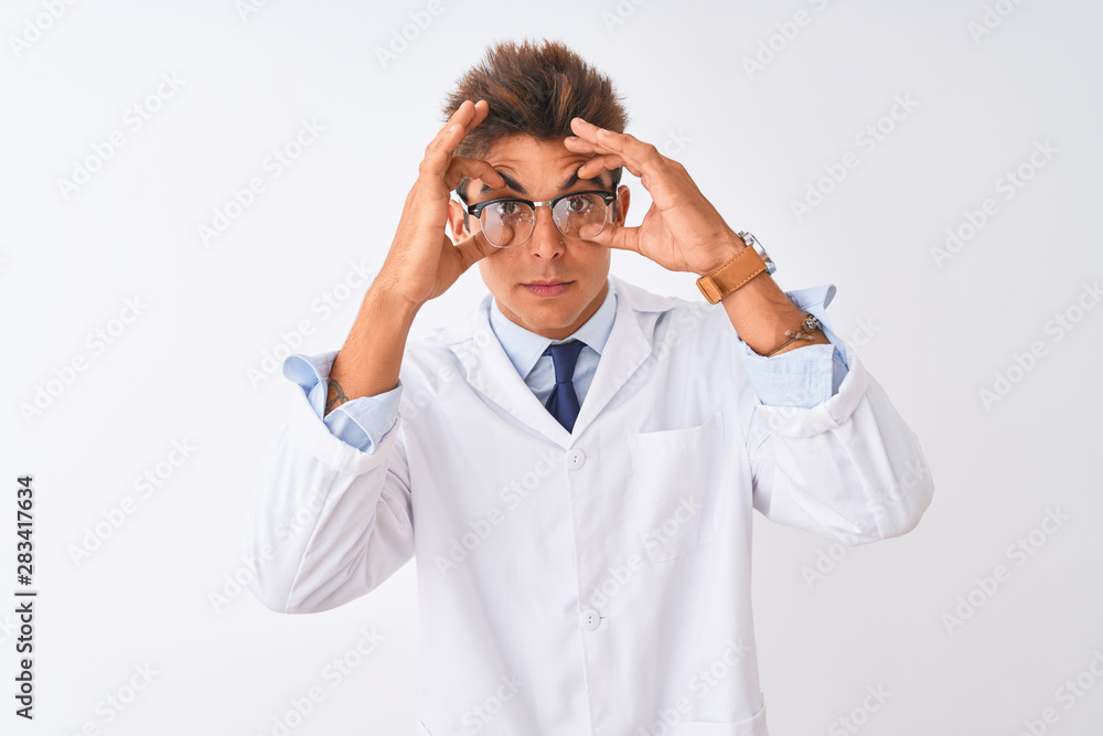 Young handsome sciencist man wearing glasses and coat over isolated white background Trying to open eyes with fingers, sleepy and tired for morning fatigue Young handsome sciencist man wearing glasses and coat over isolated white background Trying to open eyes with fingers, sleepy and tired for morning fatigue