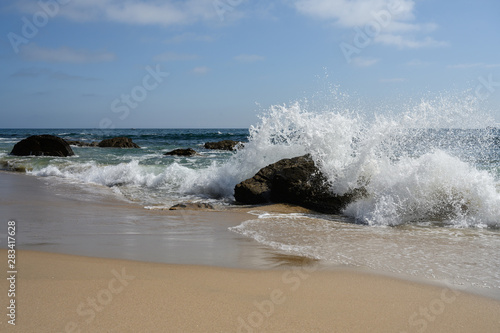 ocean waves on rock in El Matador Beach, Malibu with a sunny blue day in summer time