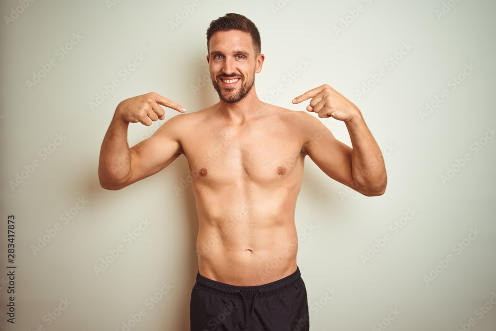 Young handsome shirtless man over isolated background looking confident with smile on face, pointing oneself with fingers proud and happy.