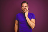 Young man wearing casual purple t-shirt over lilac isolated background touching mouth with hand with painful expression because of toothache or dental illness on teeth. Dentist concept.