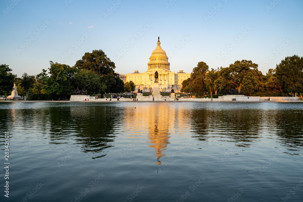 United States Capitol building at dusk sunset during a summer day, glowing from sunshine, with reflecting pond