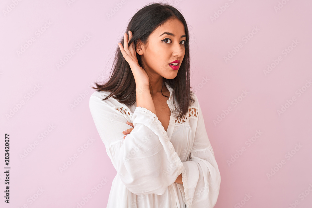 Young chinese woman wearing summer shirt standing over isolated pink background smiling with hand over ear listening an hearing to rumor or gossip. Deafness concept. Young chinese woman wearing summer shirt standing over isolated pink background smiling with hand over ear listening an hearing to rumor or gossip. Deafness concept.